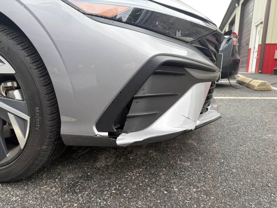 Silver Hyundai Elantra before repair, front bumper cover pulled away at the corner below the headlight