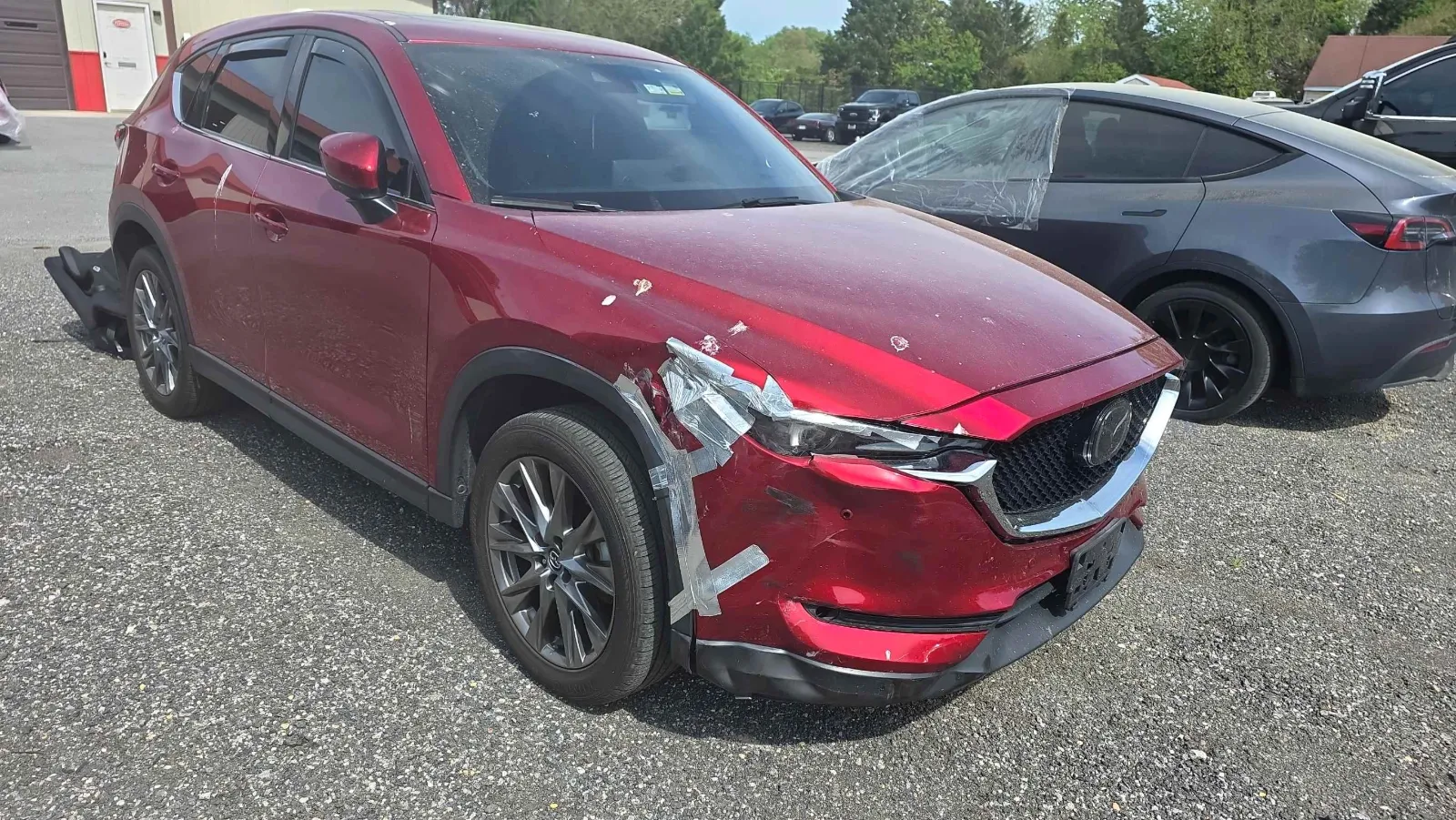 Red Mazda SUV before repair, with front bumper and fender collision damage