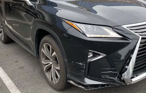 Lexus SUV with a scraped and cracked front bumper before repair