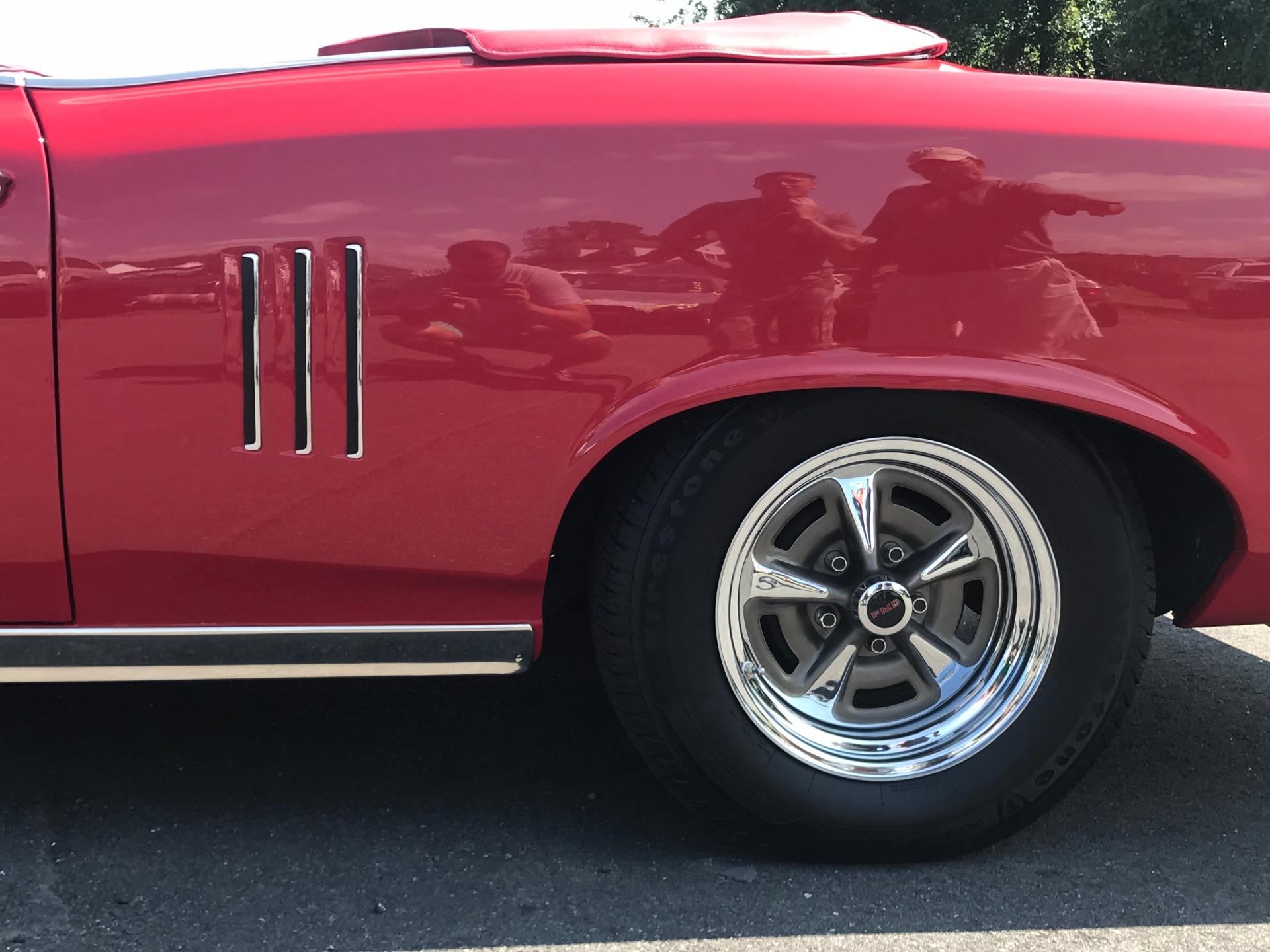 Restored red Pontiac Firebird quarter panel and chrome wheel detail