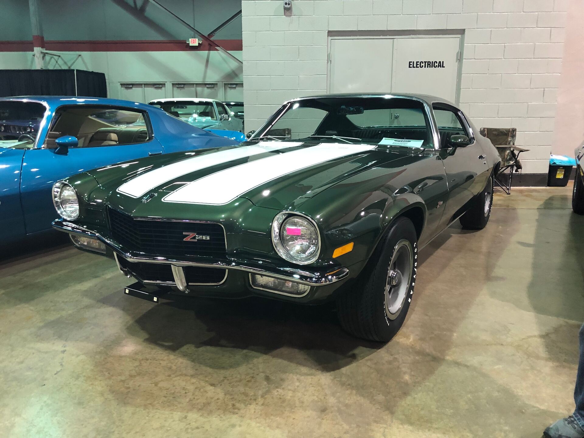 Restored dark green Camaro Z28 with white stripes at car show